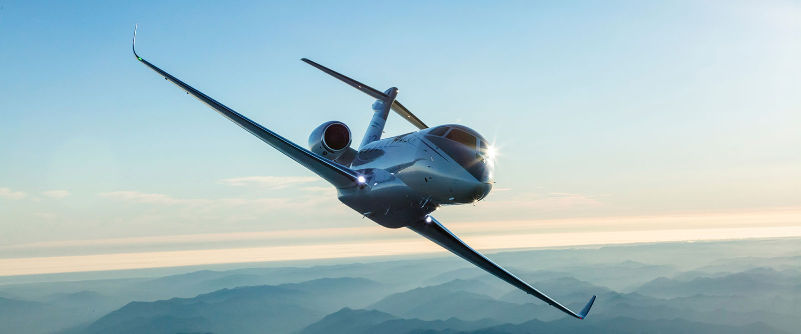 G280 banking sharply over misty-shrouded mountains at dusk