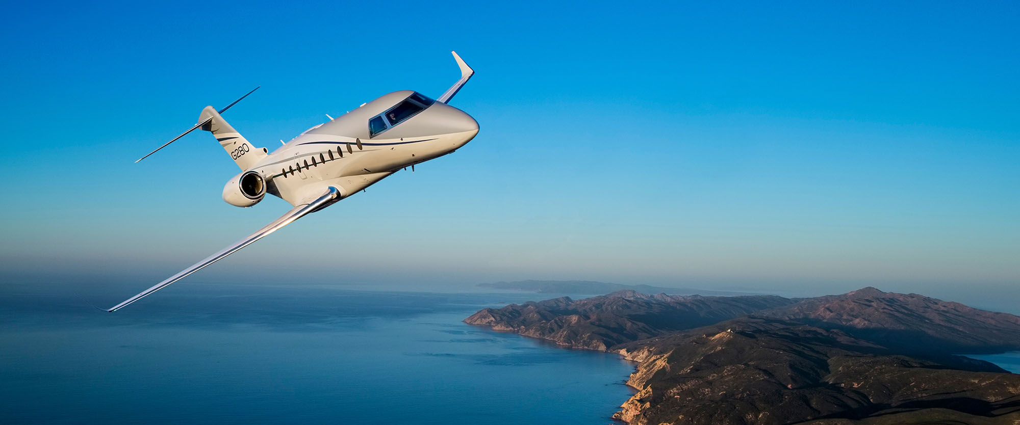 G280 banking in bright morning sunlight above distant islands