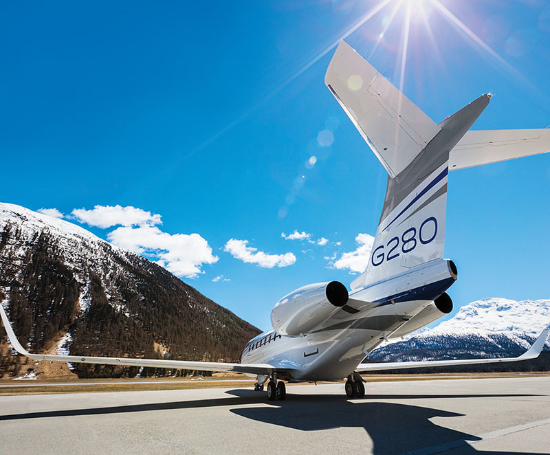 G280 taxiing in bright sunlight at an airport in mountainous terrain