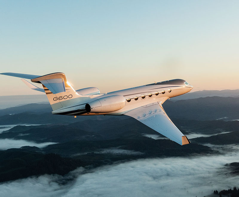 G600 flying over low hills rising above cloud-filled valleys