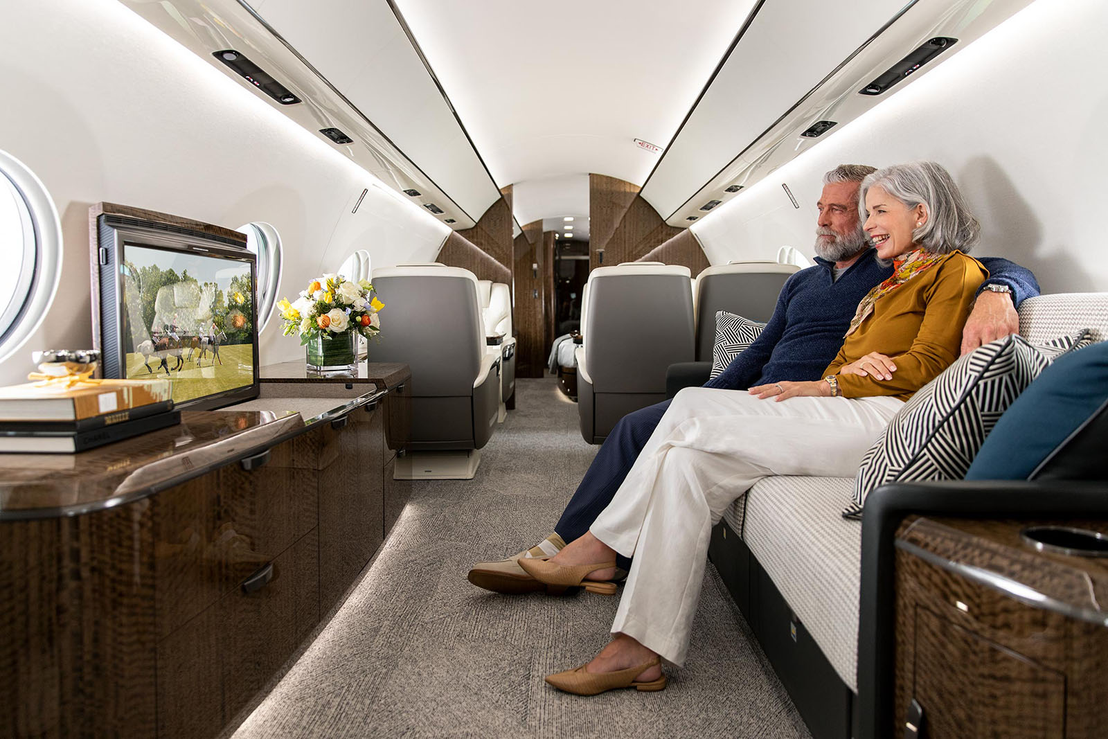 A smiling couple watches television on a Gulfstream G700