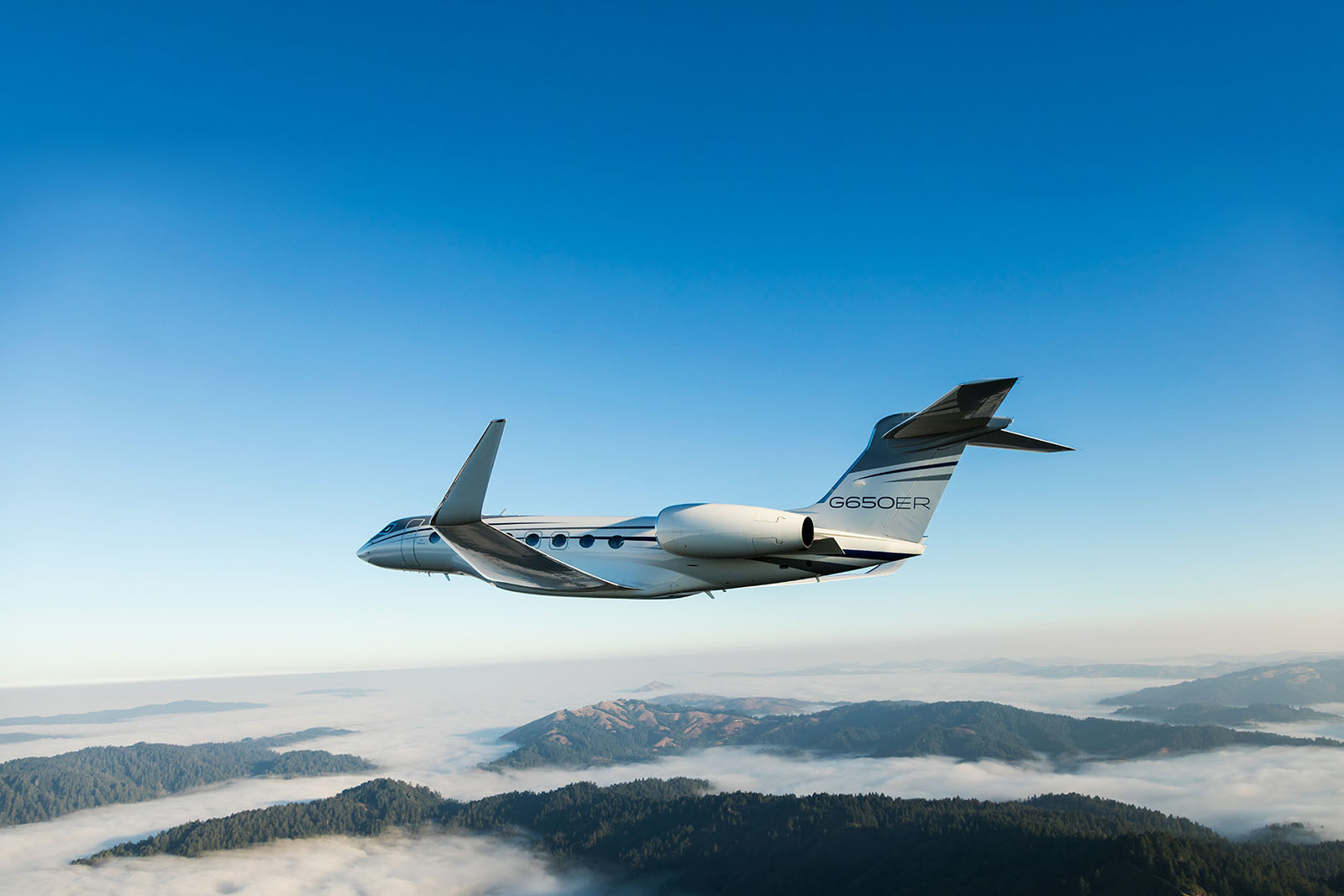 G650ER private jet for sale flying through a clear blue sky