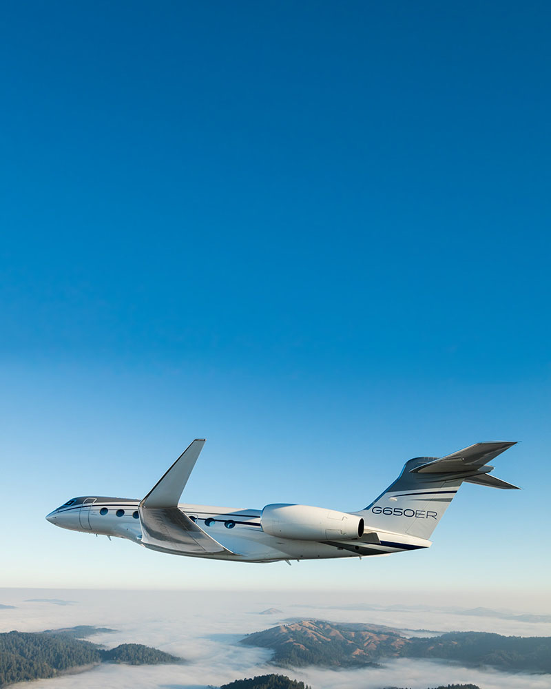 G650ER private jet for sale flying through a clear blue sky