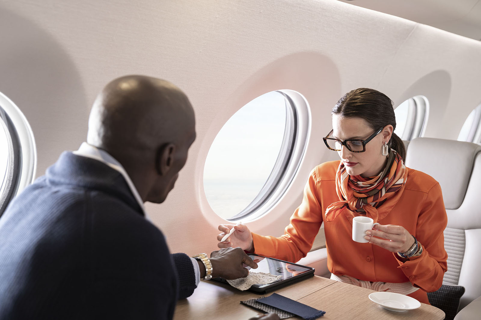 Fashion executives sitting across a G400 work surface before a large panoramic window consult a tablet.