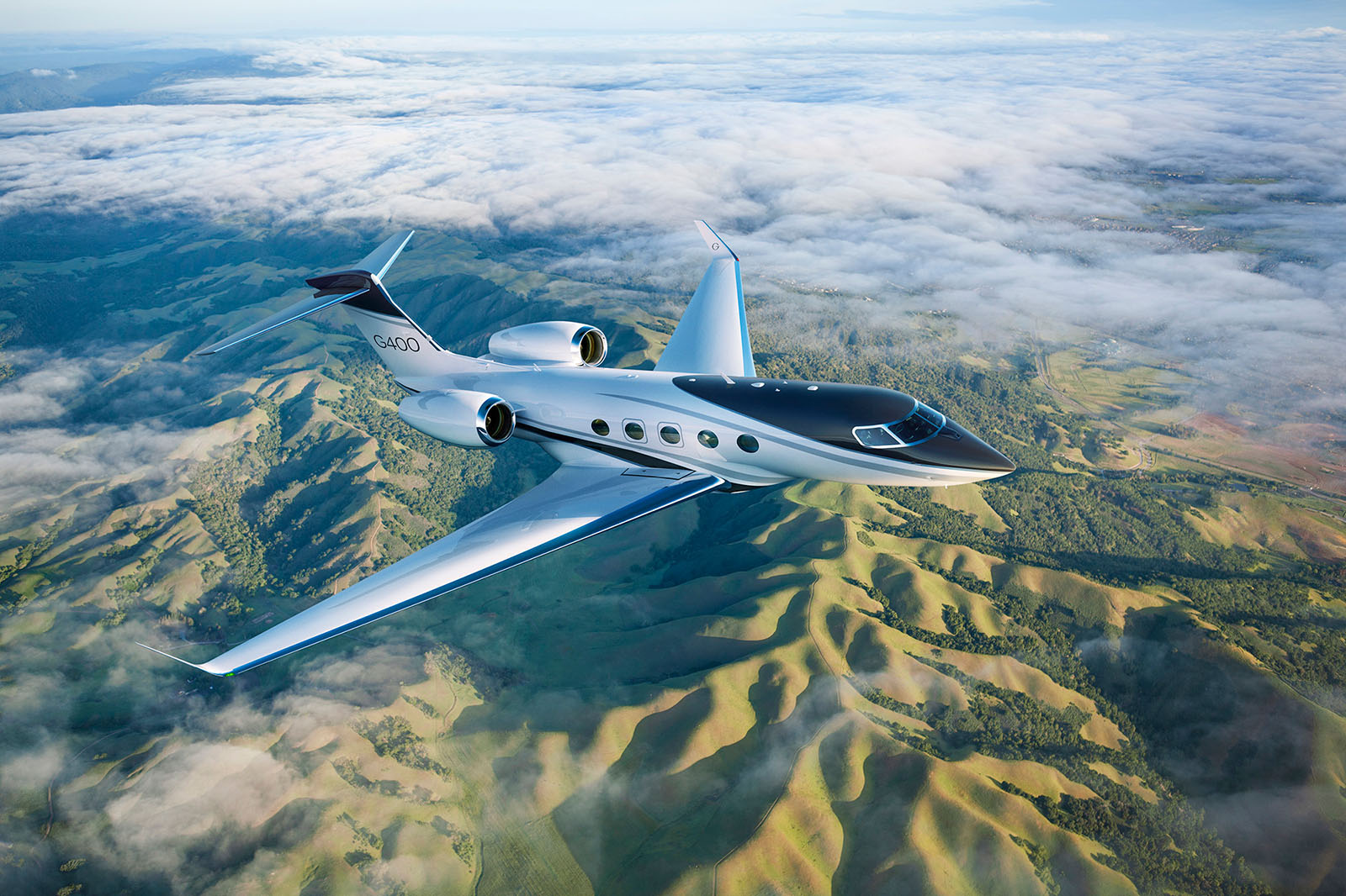 G400 cruising over green hilly terrain.