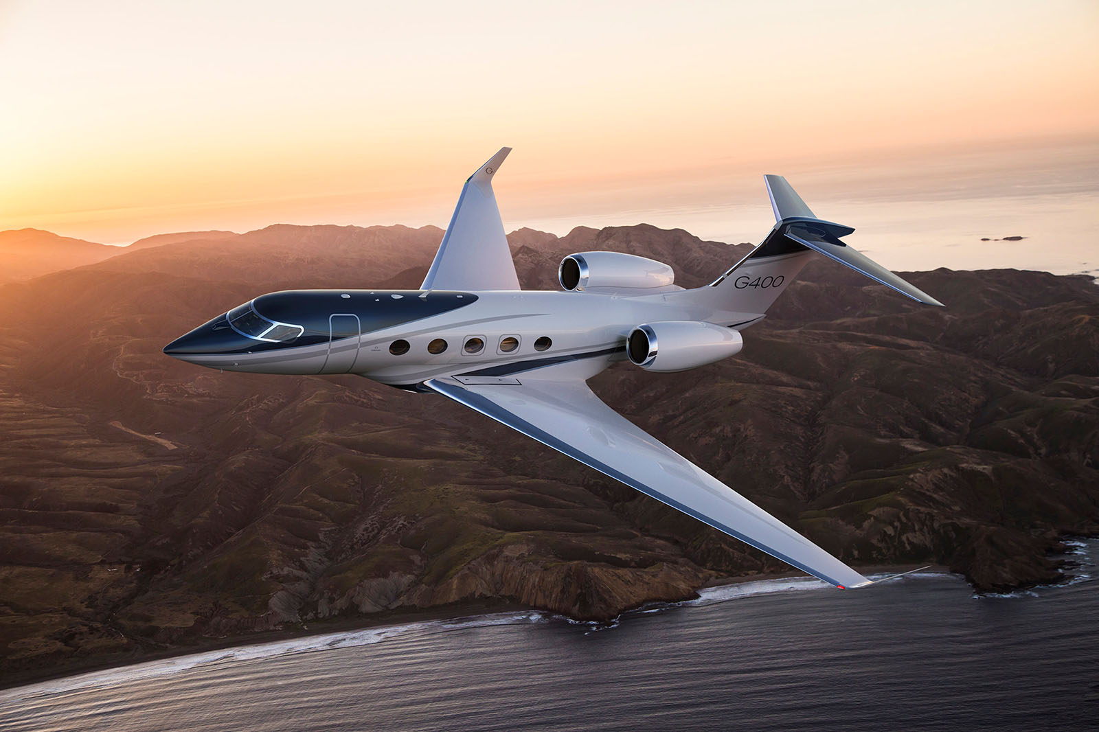 G400 flies over a mountainous coastal landscape as the sun rises