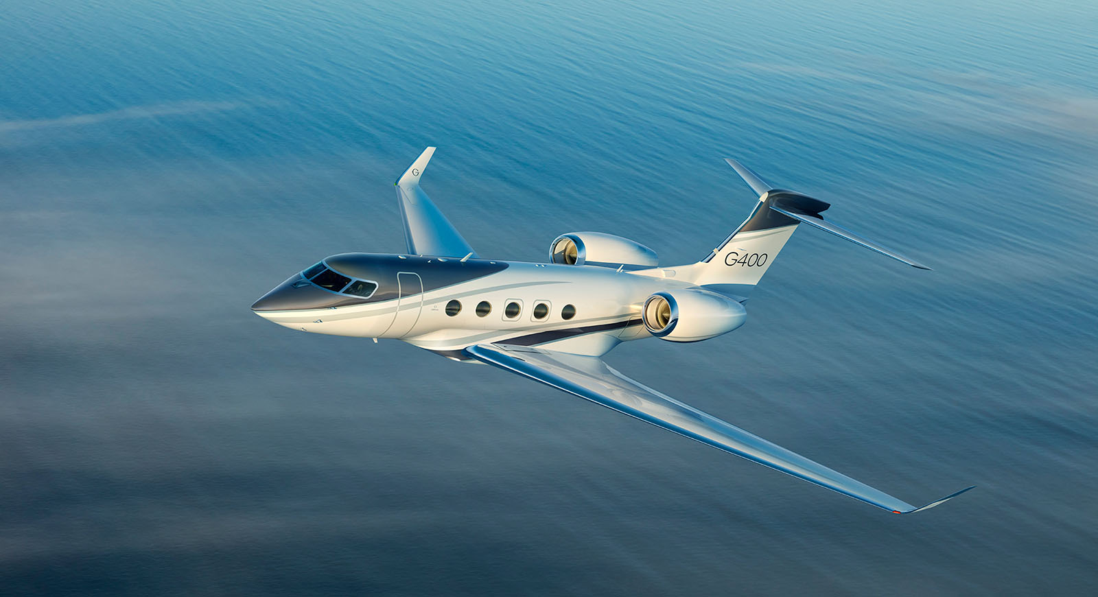 G400 cruising over a large body of water at sunrise
