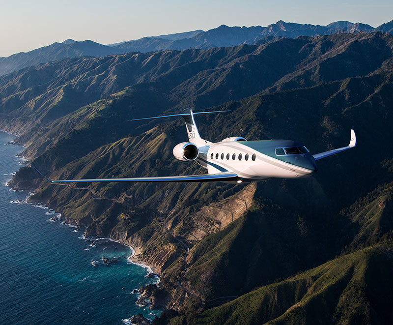 G800 gaining altitude while flying next to a seaside mountain range